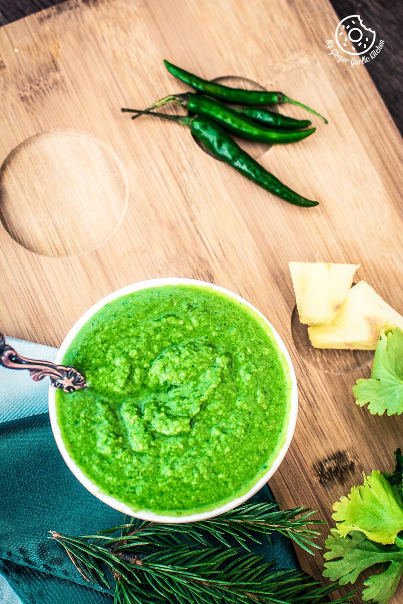 there is a bowl of green coriander chutney with a spoon next to it