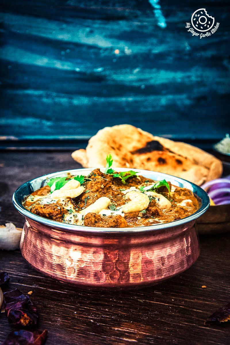 a bowl of restaurant style shahi kaju curry with some naan and salad