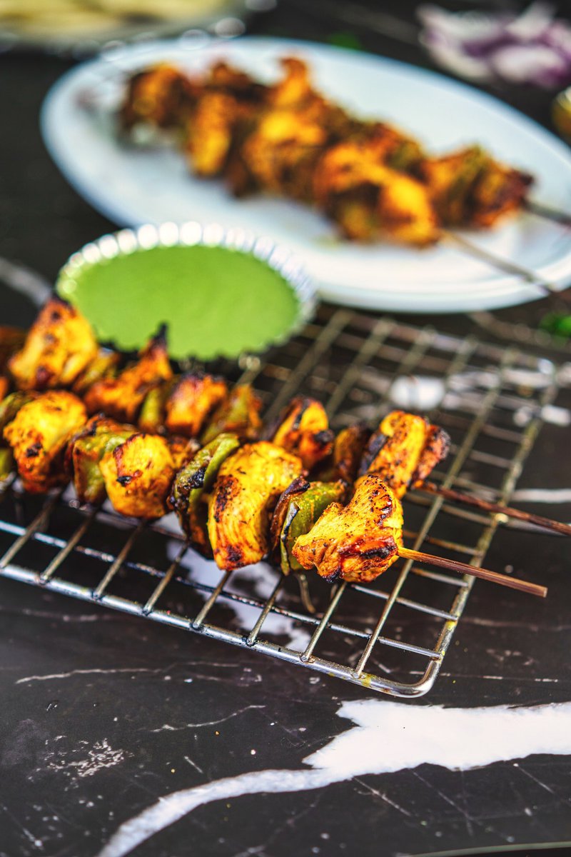 A platter displaying beautifully grilled chicken tikka kebabs, seasoned with aromatic spices and served with fresh lemon wedges.