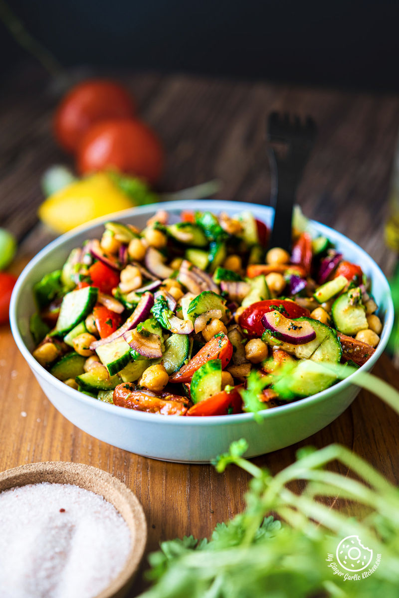 a closeup shot of chickpea salad served in a light grey ceramic bowl