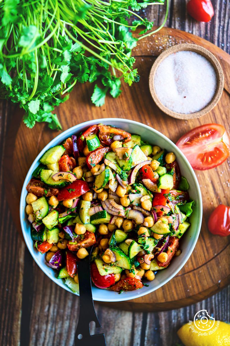 overhead shot of chickpea salad served in a light grey ceramic bowl with cilantro and salt on the side