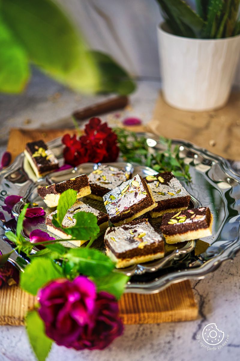 chocolate burfis in a metal plate with flowers on the side