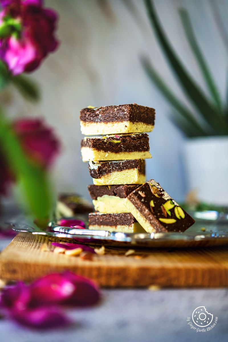 five chocolate burfis piled with one burfi on the side