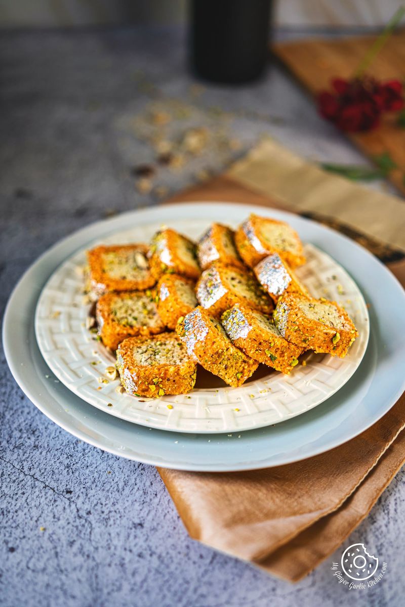 six coconut burfi rolls served in a white plate