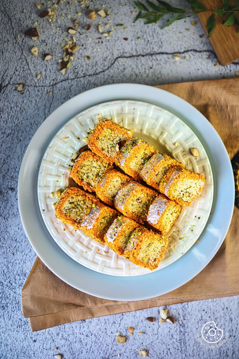 overhead shot of six coconut burfi rolls served in a white plate