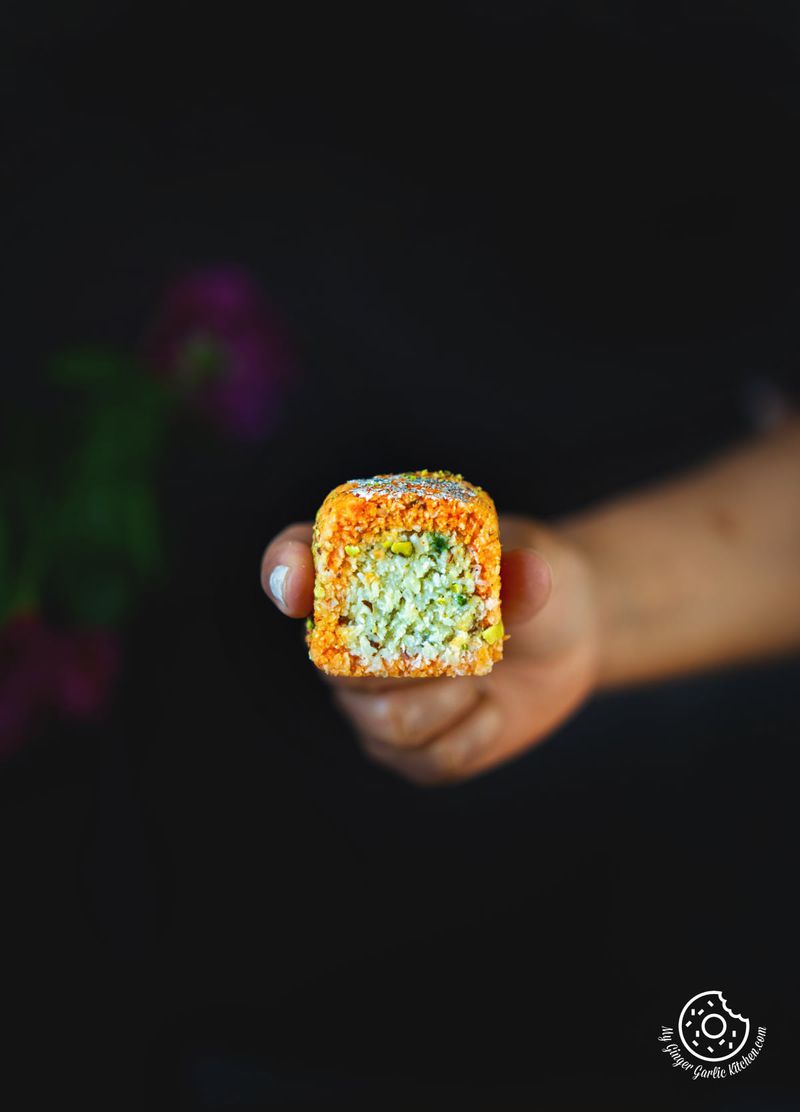 a hand holding a coconut burfi roll