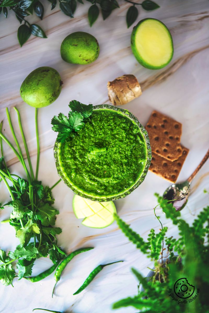 overhead photo of a green mango chutney with raw mango slices, and crackers on the side
