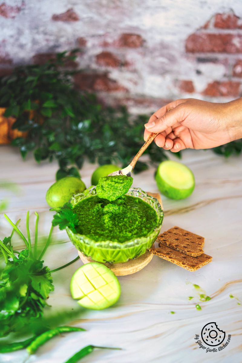 photo of a person dipping a spoon into a bowl of raw mango chutney
