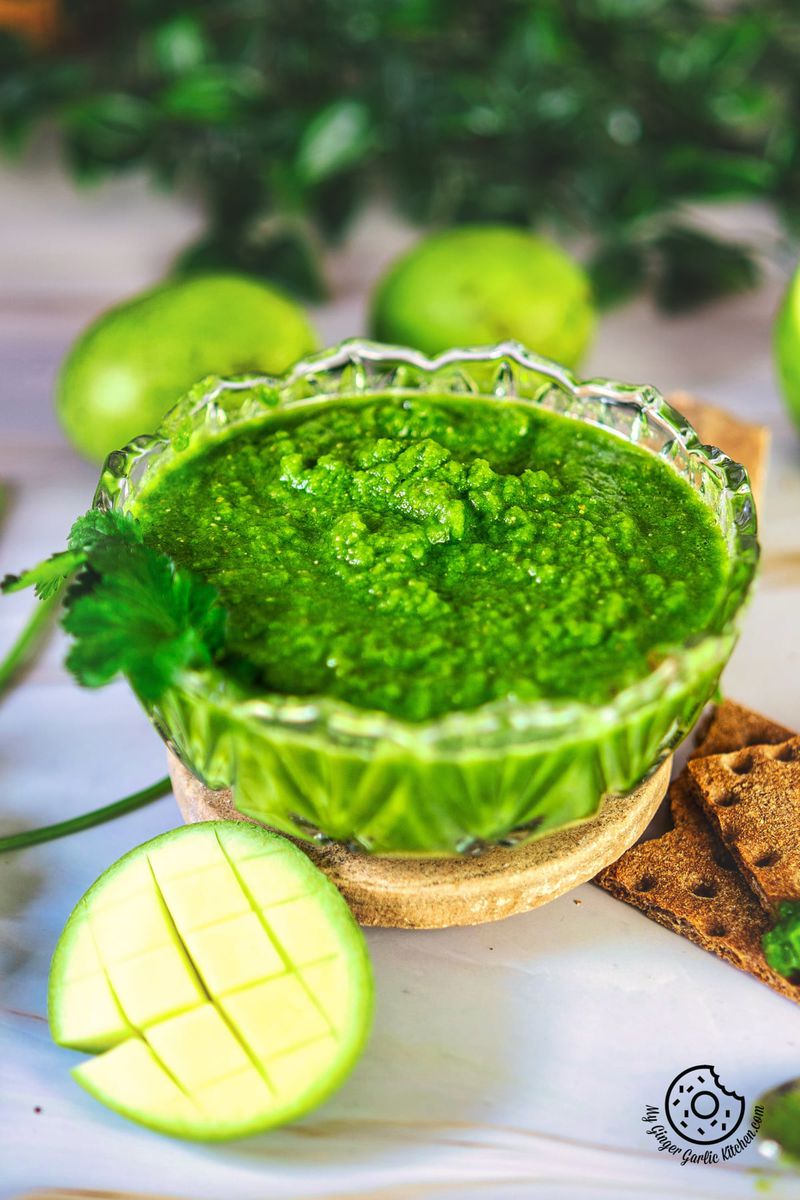 photo of a bowl of green mango chutney with a slice of raw mango on the side