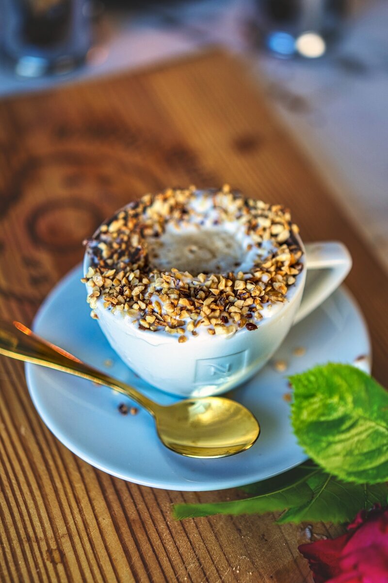 Gourmet hazelnut affogato with caramelized nut topping served in white cup with gold spoon on blue saucer premium coffee dessert experience