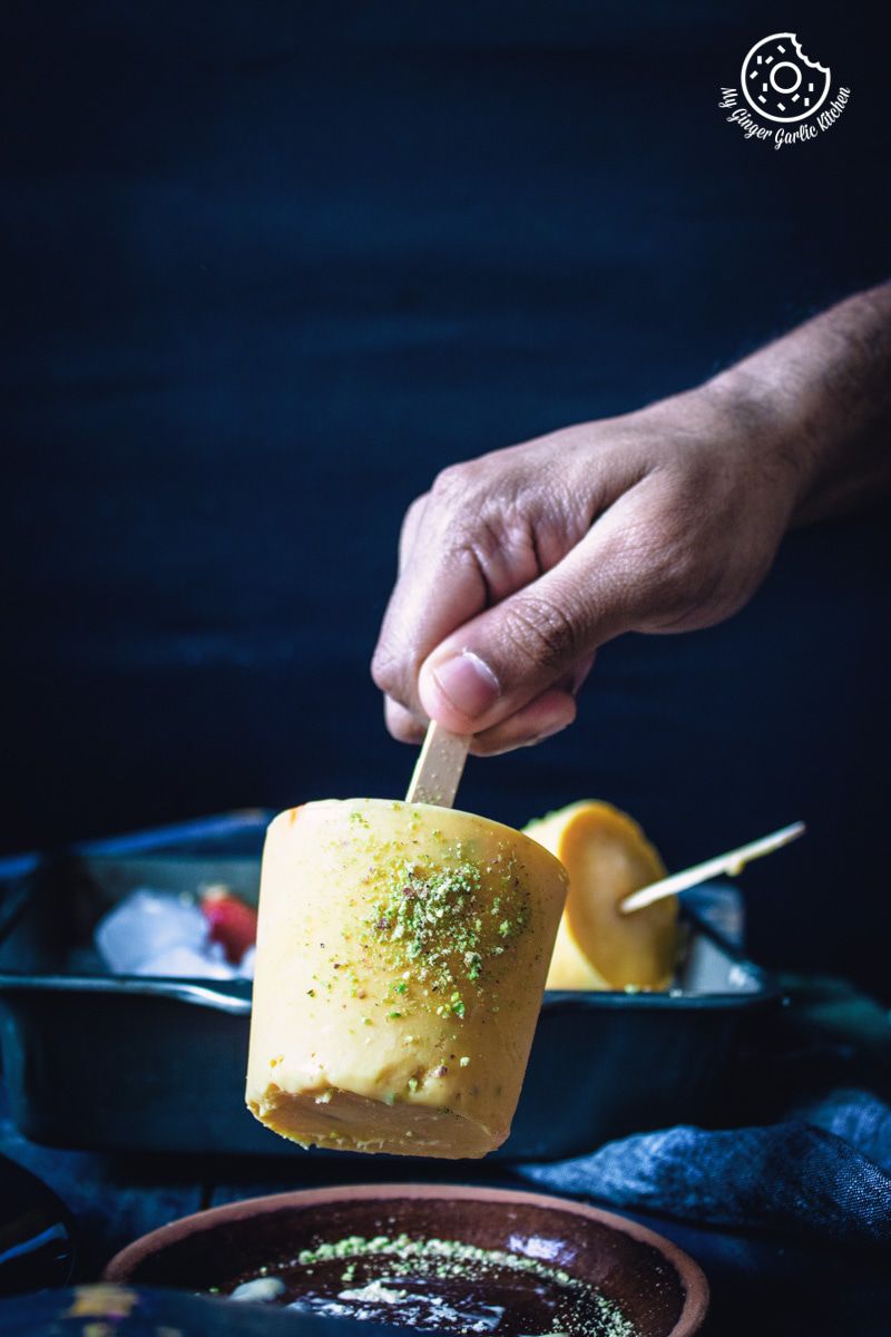 someone is holding a mango kulfi popsicle