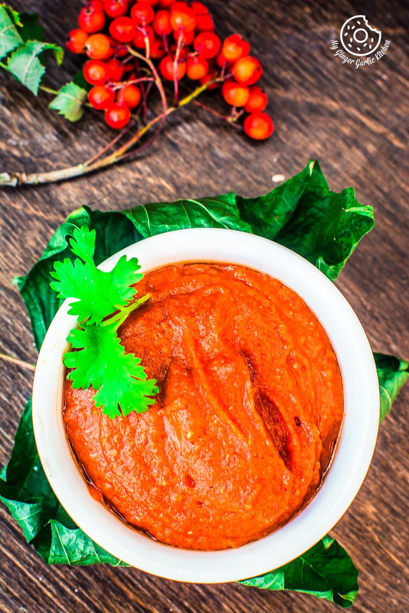 there is a bowl of rajasthani lehsun ki chutney with a sprig of cilantro