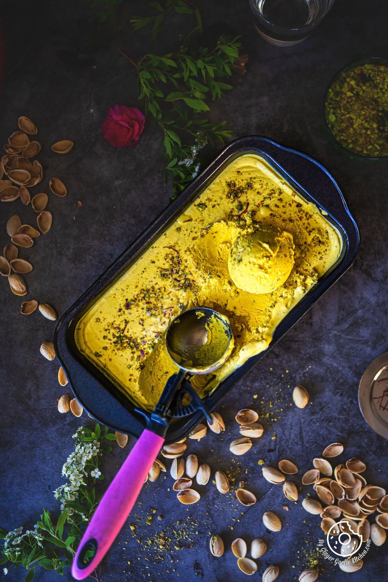 overhead shot of kesar pista ice cream container with one ice cream scoop on top