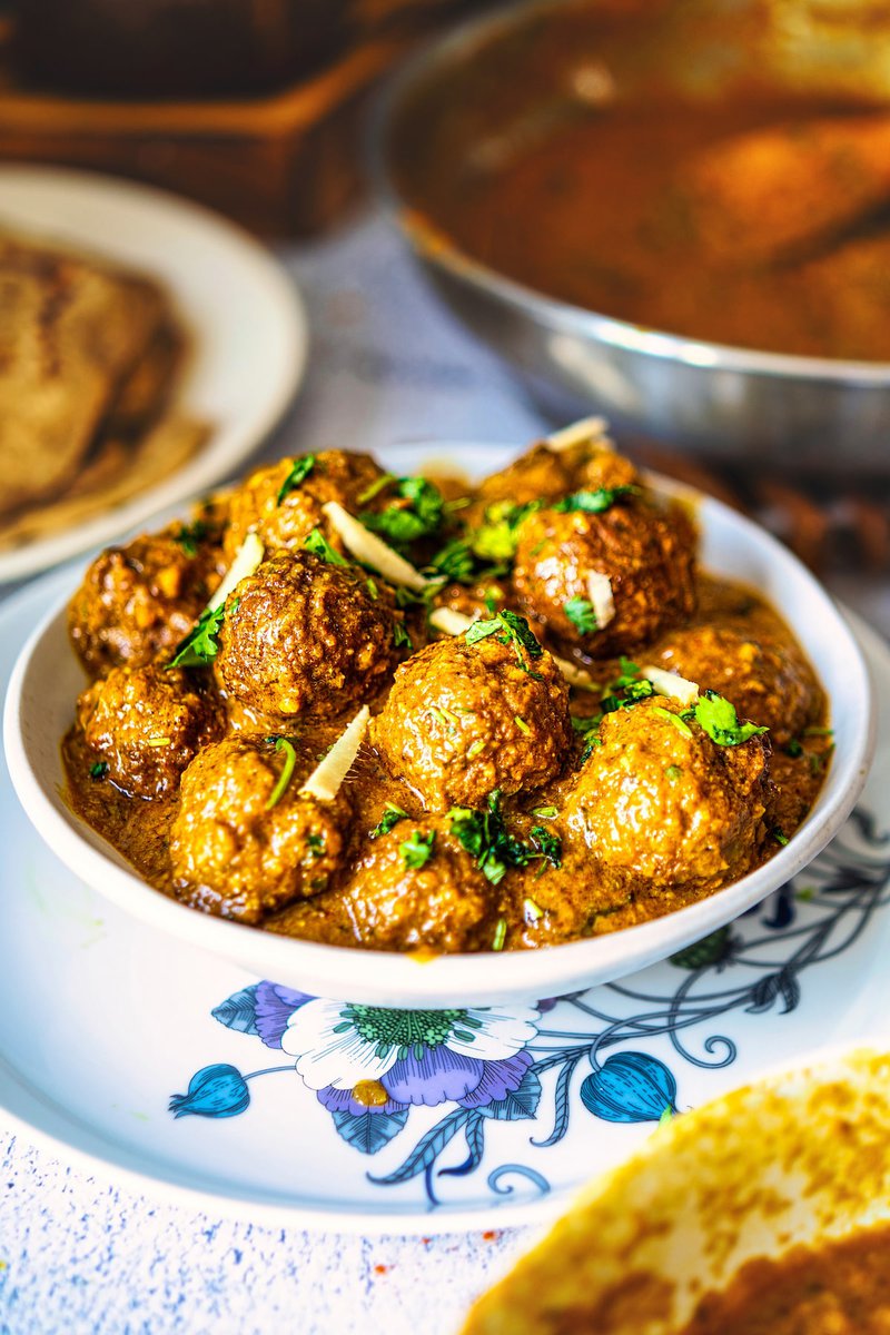 Homemade lauki kofta curry served in white bowl, garnished with fresh cilantro and ginger julienne in rich Indian gravy sauce, authentic vegetarian dish