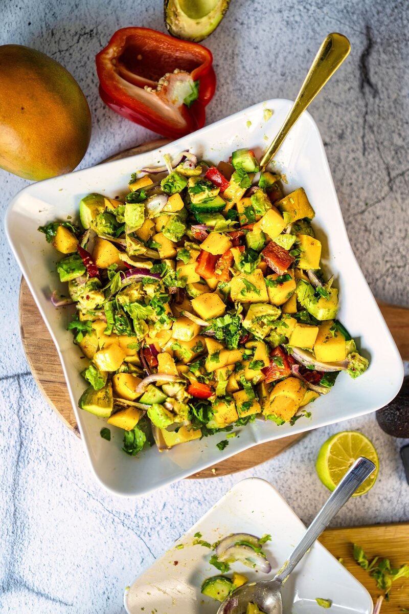 Top view of vibrant mango avocado salad with bell pepper red onion and lime in white bowl summer vegan salad recipe