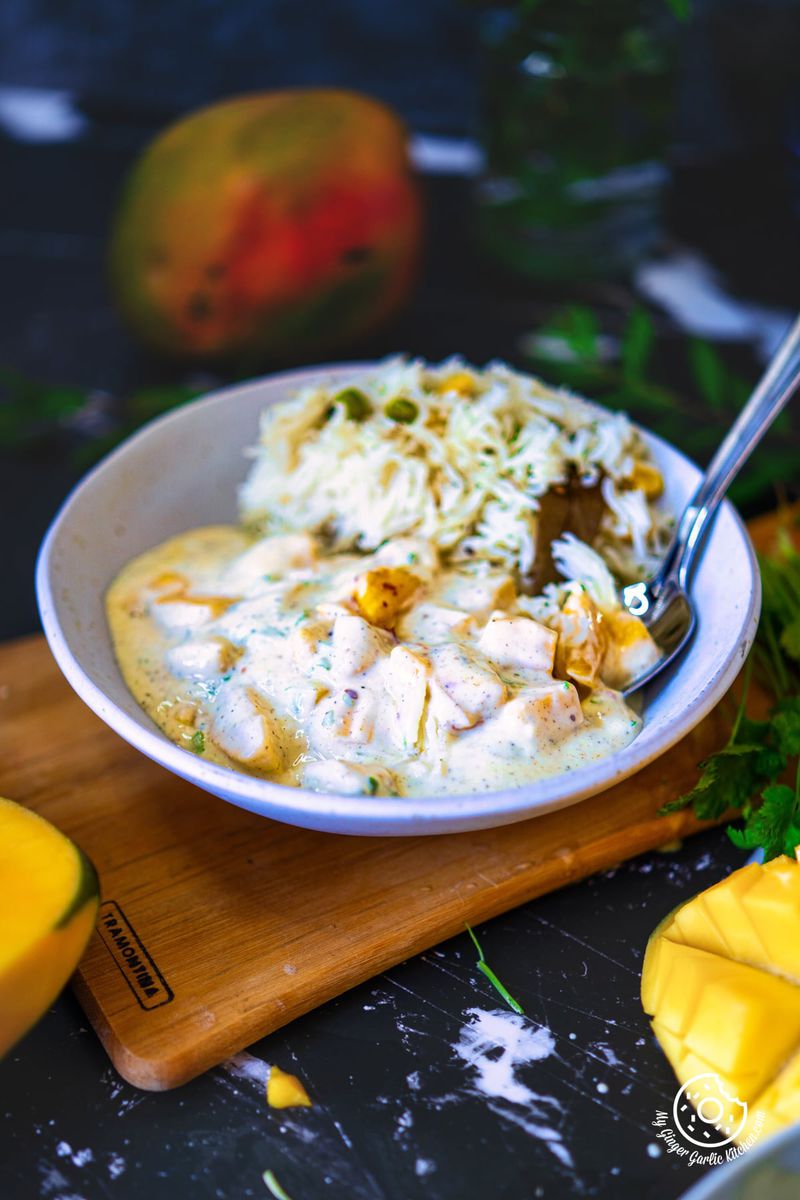 Mango raita served in a white bowl with some pulao on the side