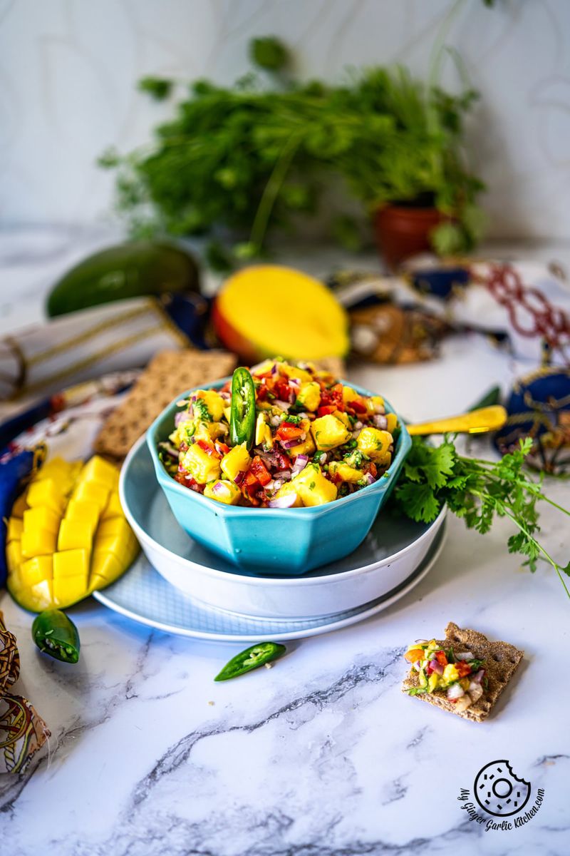 mango salsa in a light blue color bowl and a couple of manago slices on the side