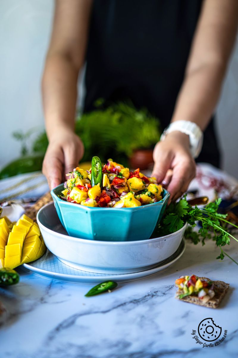 a female holding a light blue mango salsa bowl
