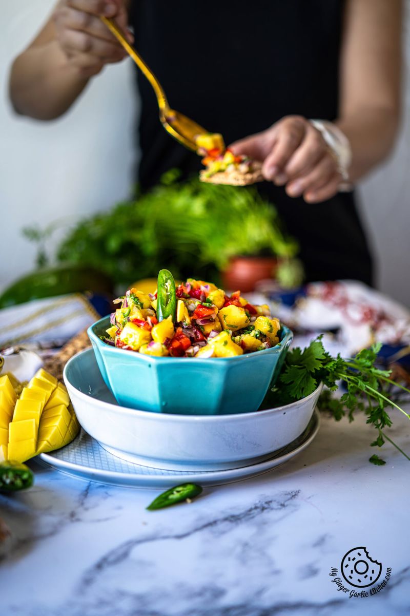 a light blue mango salsa bowl and a female in the background