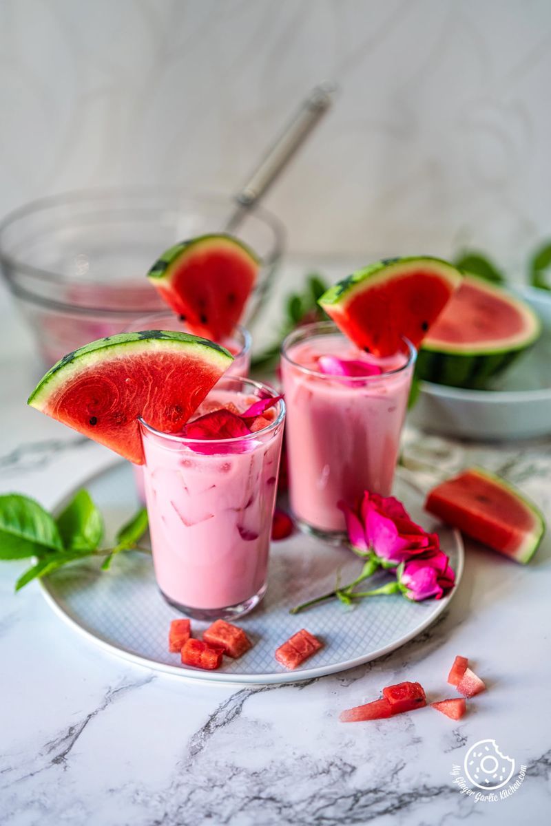 3 glasses with mohabbat ka sharbat in a grey ceramic plate and watermelon chunks on the side