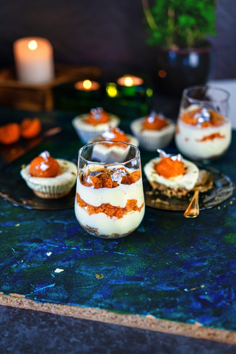 Festive no bake motichoor cheesecake parfait in a glass, layered with cheesecake cream and motichoor ladoo pieces, with candles and mini cheesecakes