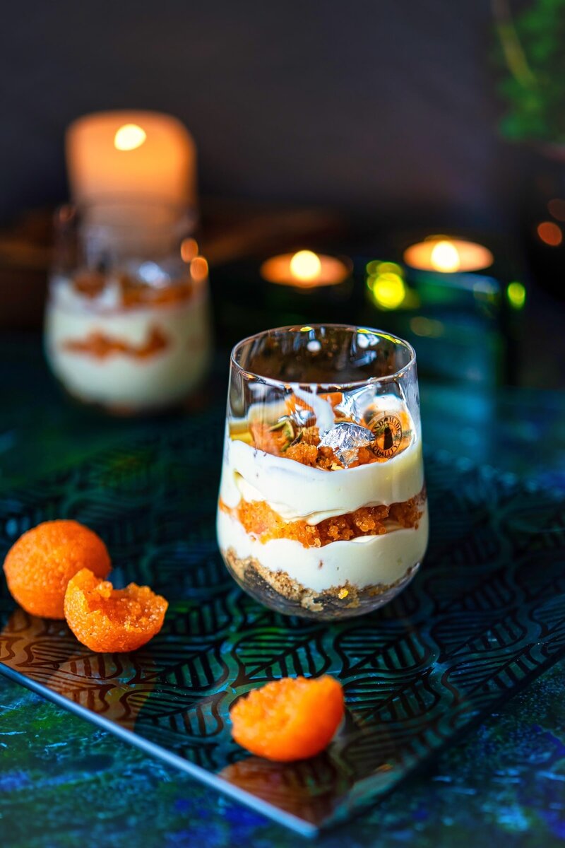 No bake motichoor cheesecake in a glass topped with silver leaf and garnished with motichoor ladoo, styled with candles in the background