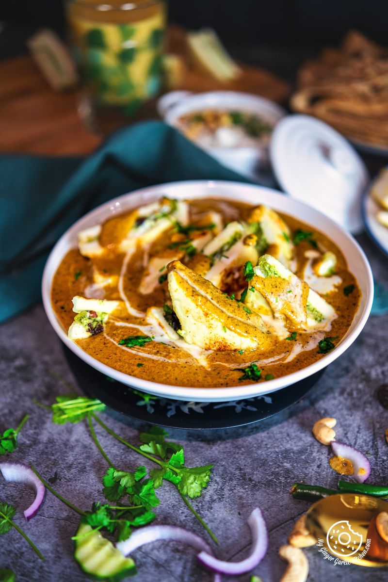 paneer pasanda curry in white bowl topped with cream and cilantro