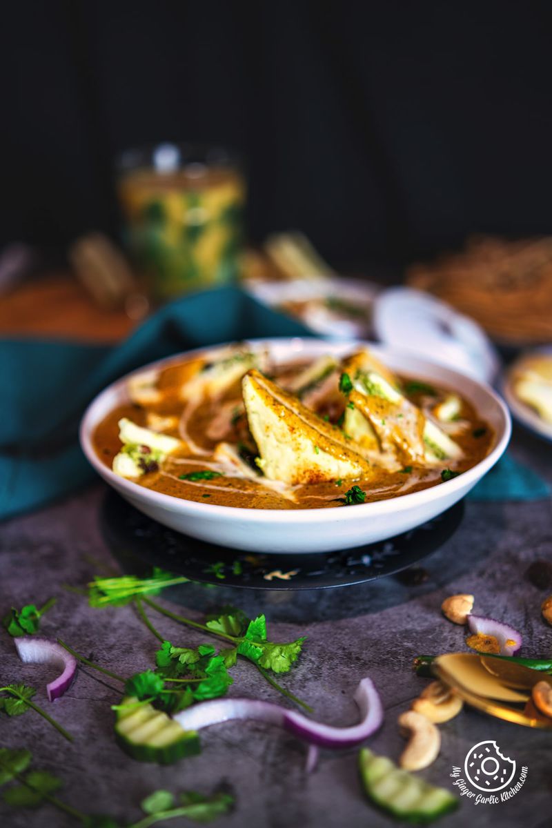 pasanda served in a white ceramic bowl with some onion and cilantro on the side