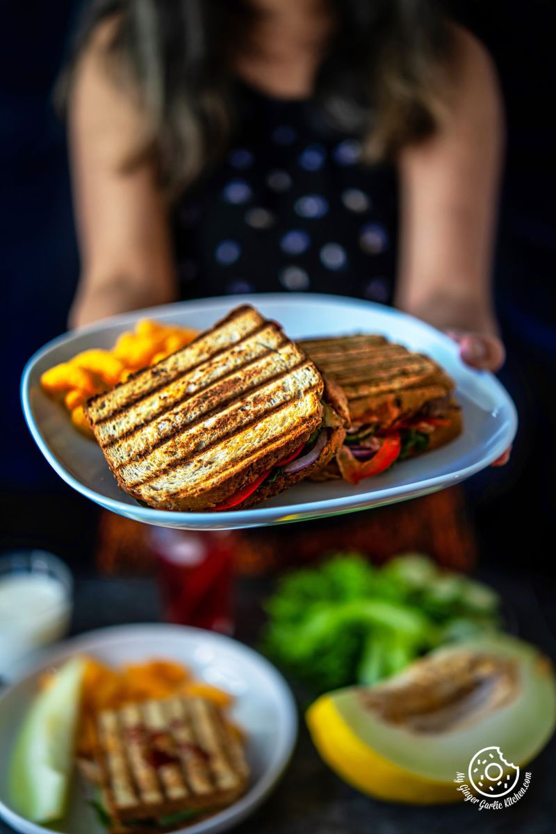 a female holding a white plate with peanut butter and veggie grilled cheese sandwiches