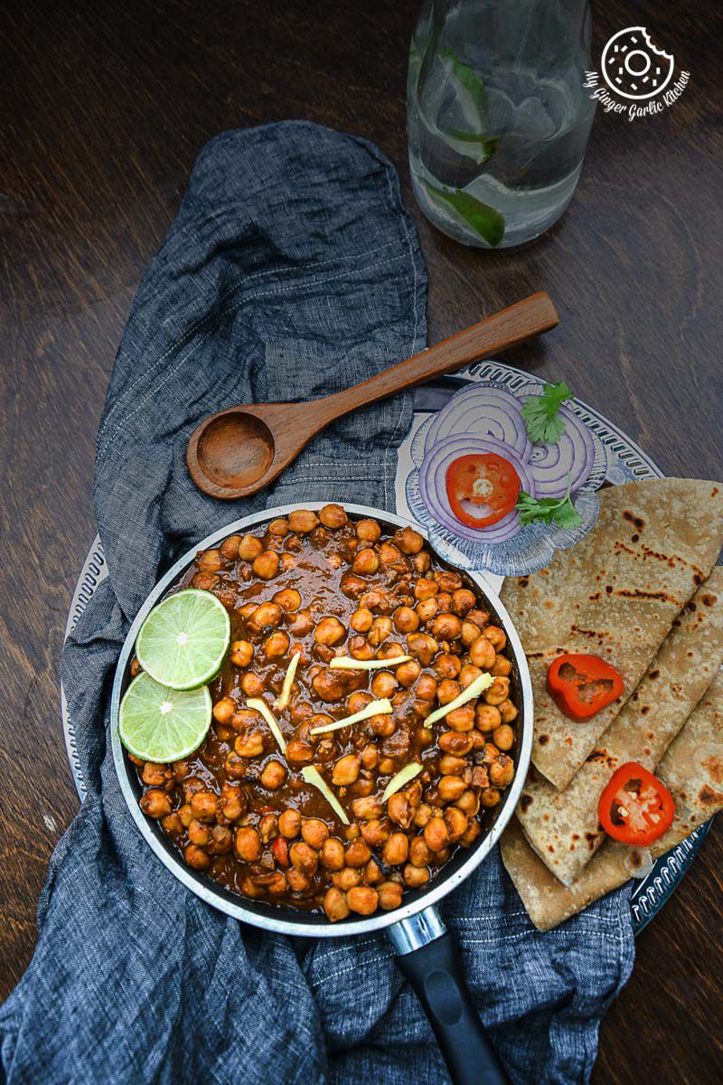 a plate of amritsari chole and parathas with a wooden spoon and a napkin