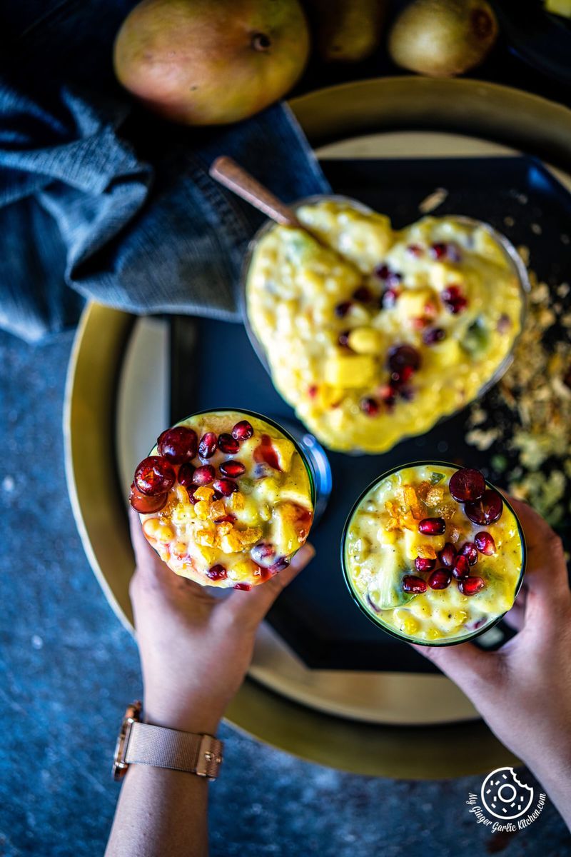 two hands holding two glasses on sago fruit custard