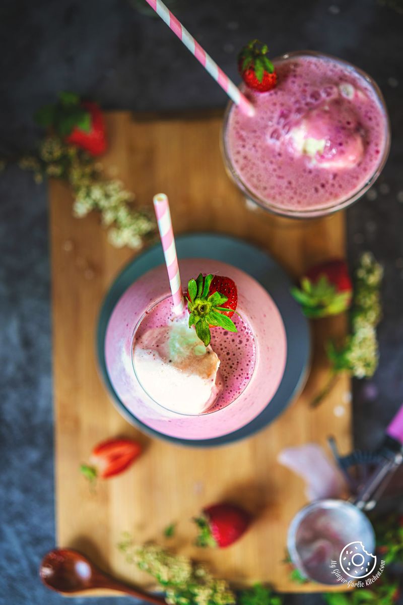 overhead shot of two strawberry milkshake glasses topped with ice cream and strawberry