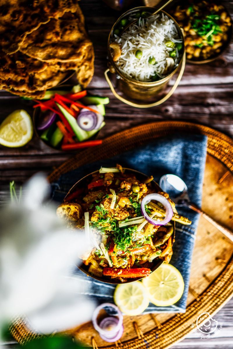 overhead vegetable jalfrezi served in a brass bowl along with a rice bowl and salad
