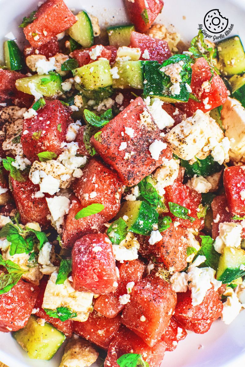 Watermelon Cucumber Feta Salad on white plate with golden serving spoons