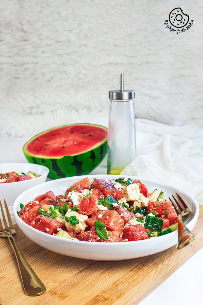Watermelon Cucumber Feta Salad on white plate with golden serving spoons